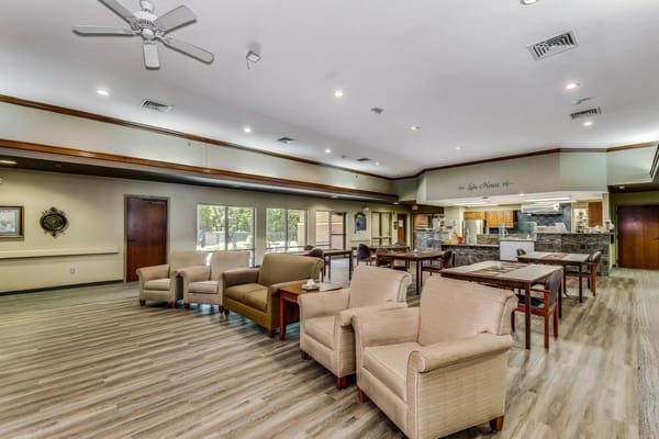 Comfortable seating area in the common room with dining tables and a kitchen in the background.