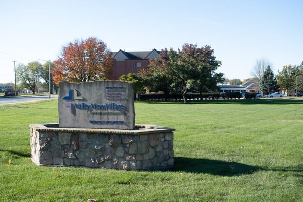 Entrance sign of Valley View Village surrounded by greenery.