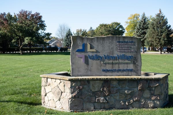 Stone sign of Valley View Village in a grassy area