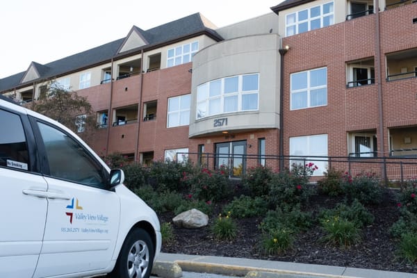Exterior view of Valley View Village building with landscaped garden and vehicle in front.