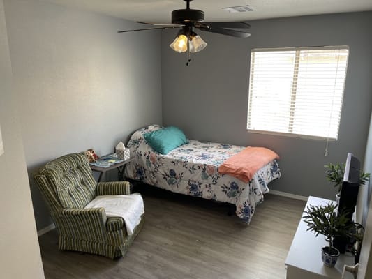 A cozy private resident room with a bed and chair