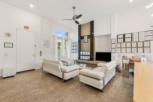 Modern living room with white sofas and a large wall-mounted TV.