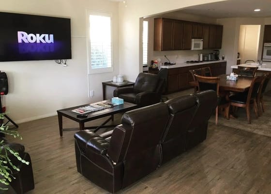 View of a living room with a TV, seating area, and dining space.