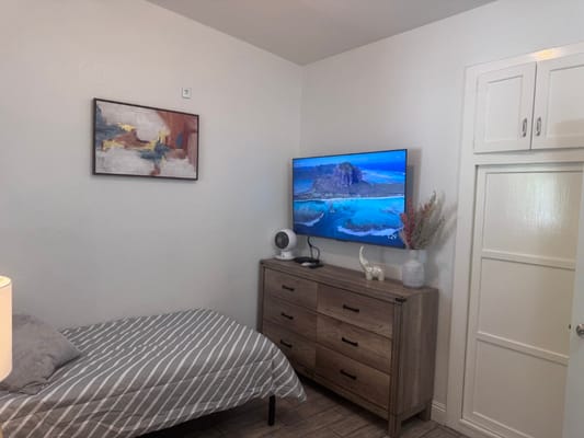 A cozy room with a bed, dresser, and TV.