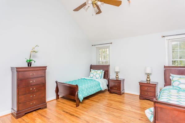 Brightly decorated bedroom with two twin beds and dresser.