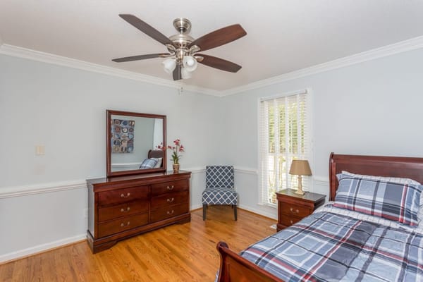 Bright and inviting bedroom with a wooden dresser and bed