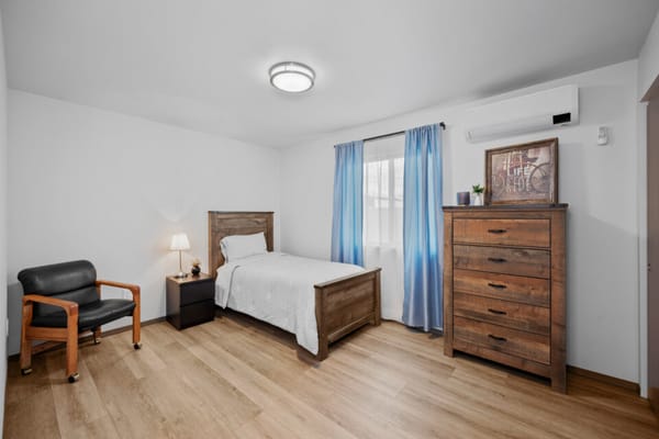 Well-furnished bedroom with bed, chair, and dresser