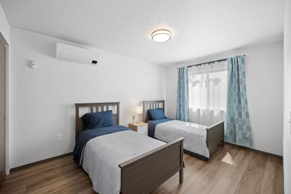 A clean, bright bedroom with two beds and natural light.