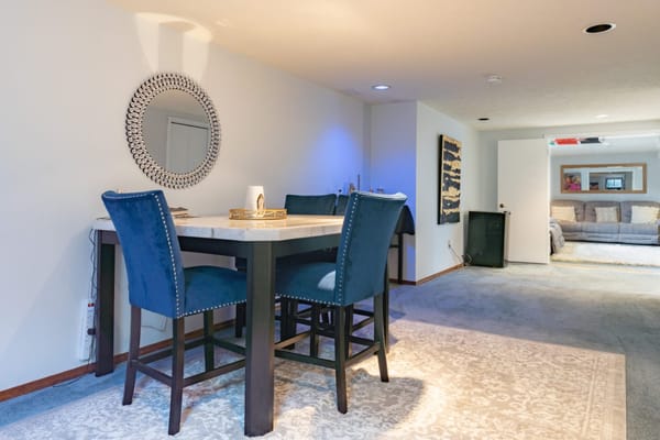 Cozy dining area with blue chairs and a mirror.