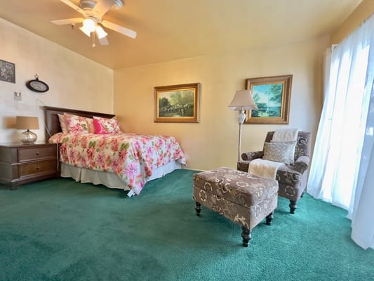 Spacious bedroom with floral bedding and green carpet