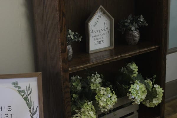 Decorative shelf with plants and a family sign