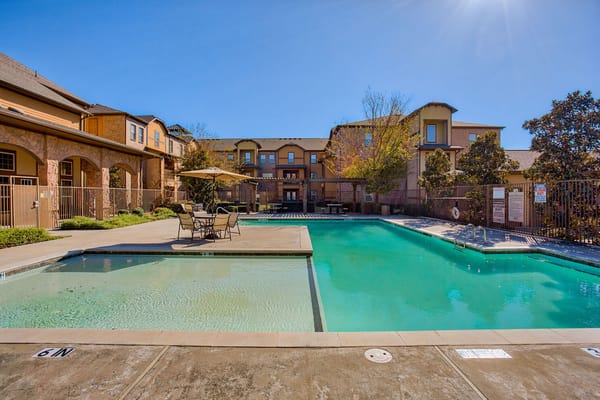 Swimming pool area with lounge chairs and building in background