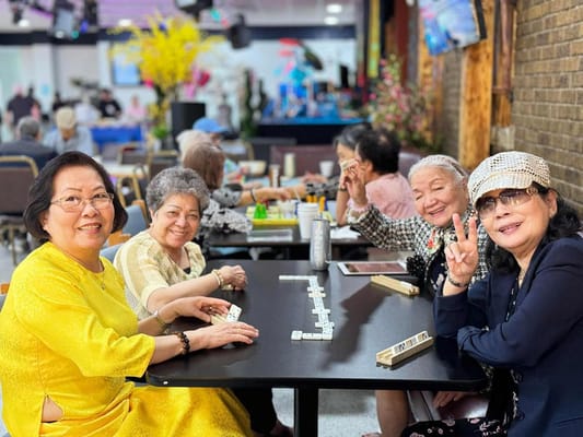 Four seniors enjoying a game at a communal table.