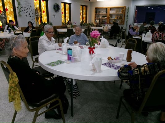 Four senior women seated at a round dining table during lunch
