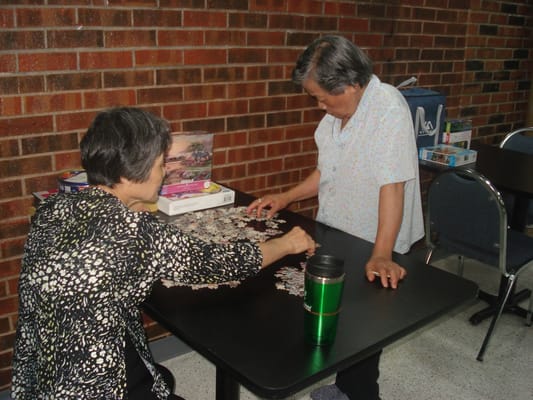 Two seniors working on a jigsaw puzzle at a table
