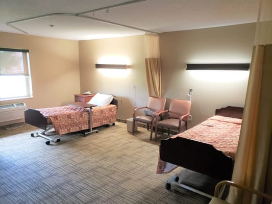 Bedroom with two hospital beds and chairs in Republic Nursing and Rehab