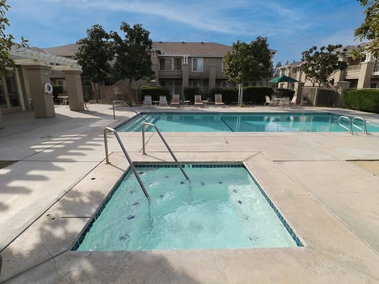 Swimming pool area with hot tub and lounge chairs