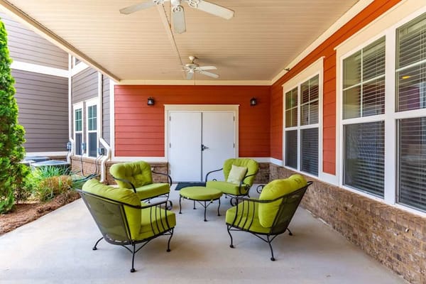 Outdoor seating area with green chairs under a porch