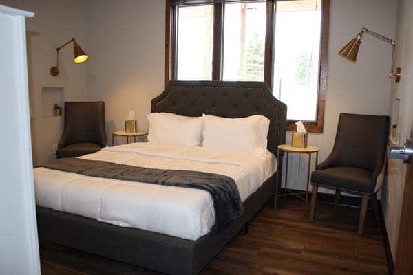 A well-furnished private room with a bed and chairs