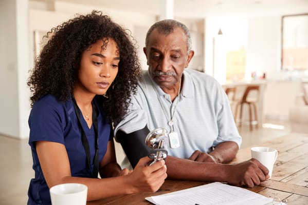 Healthcare staff assisting a resident in a cozy indoor space