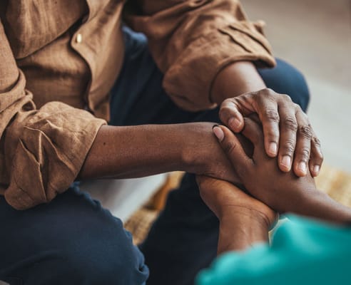 Two people holding hands in a caring gesture