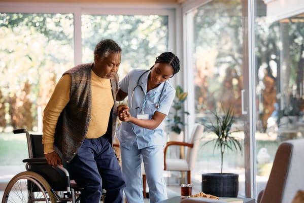 A caregiver assisting a senior resident in a bright, modern common area