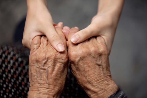 Elderly hands clasped together in a caring gesture