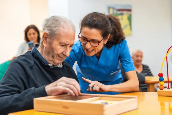 Staff assisting a resident in an activity room