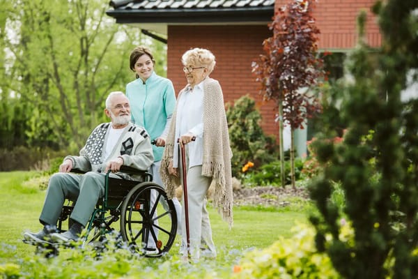 Residents enjoying a stroll in the garden with staff assistance