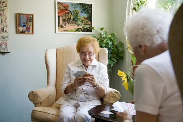 Two elderly women playing cards in a cozy living room