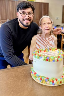 Resident celebrating with cake and staff member