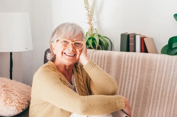 A smiling senior woman sitting comfortably indoors