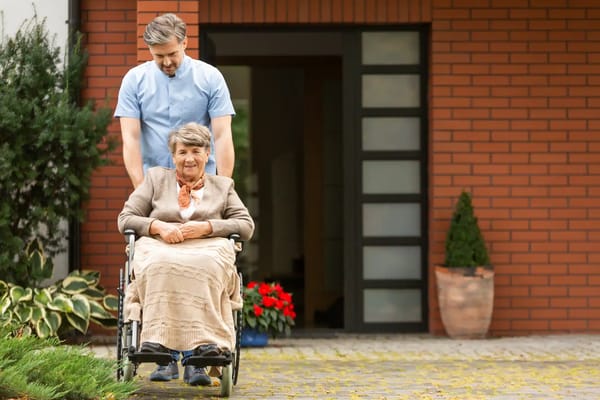 Caregiver pushing a resident in a wheelchair outdoors