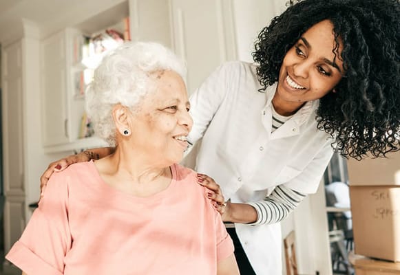 A caregiver smiling while assisting a resident