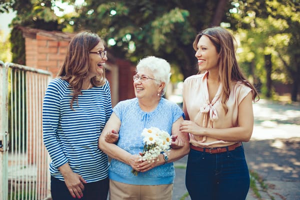 Three women smiling outdoors in a community setting