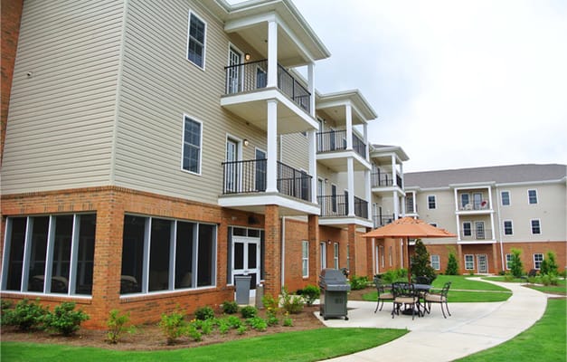 Exterior view of a senior living building with outdoor seating