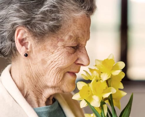 Elderly woman smiling with yellow flowers