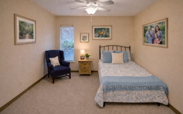 A cozy resident room with a bed and chair