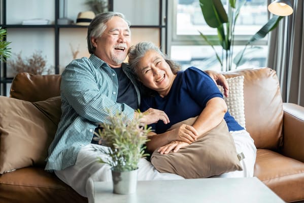 Elderly couple smiling and sitting together on a couch