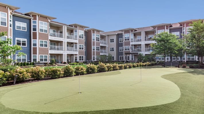 View of the outdoor space with putting green and buildings
