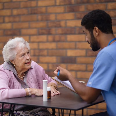 A caregiver talking with a senior resident at a table.