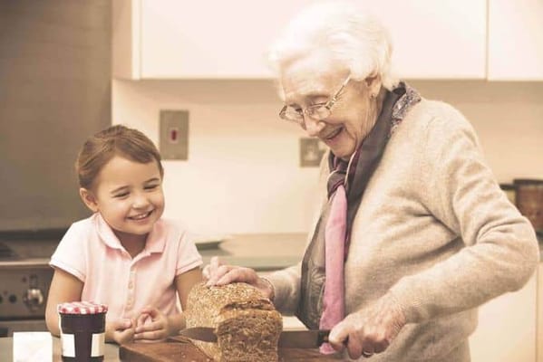 Elderly woman and child baking bread in a kitchen