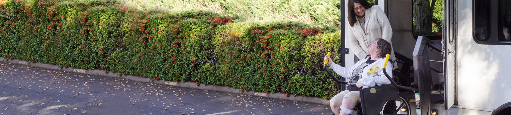 Resident in a wheelchair being assisted off a van