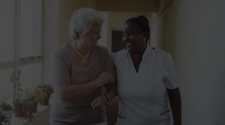 A caregiver and a resident smiling together in a hallway