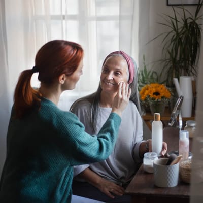 A staff member applying skincare to a resident in a bright room