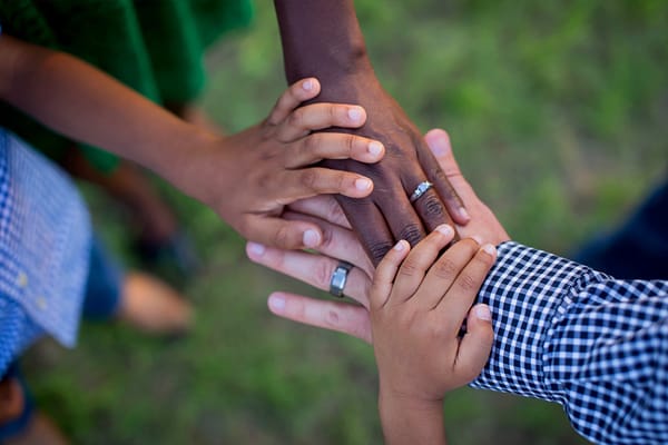 Hands of various ages stacked together outdoors