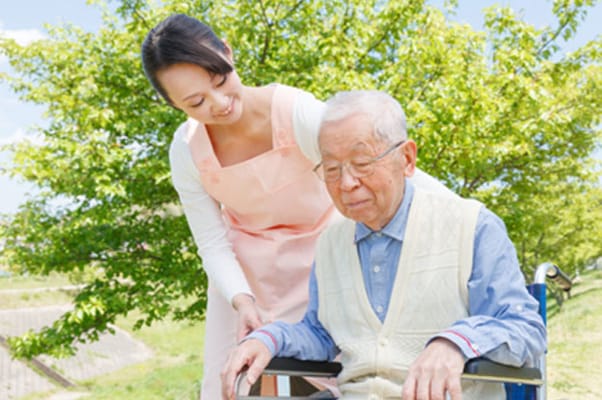 Caregiver assisting a senior outdoors in a garden