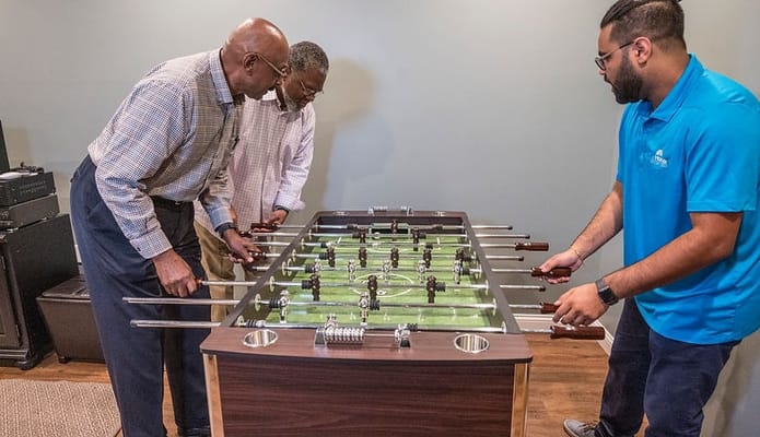 Residents engaging in a foosball game in an activity room