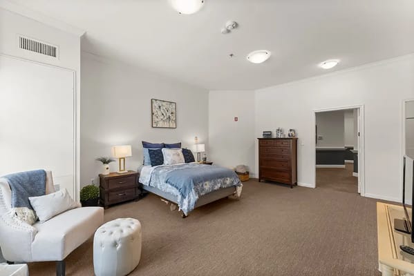 A well-furnished resident room with a bed and seating area