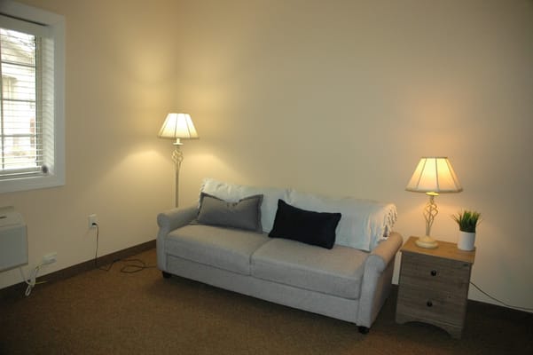 A cozy living room with a gray sofa, two lamps, and a small table.